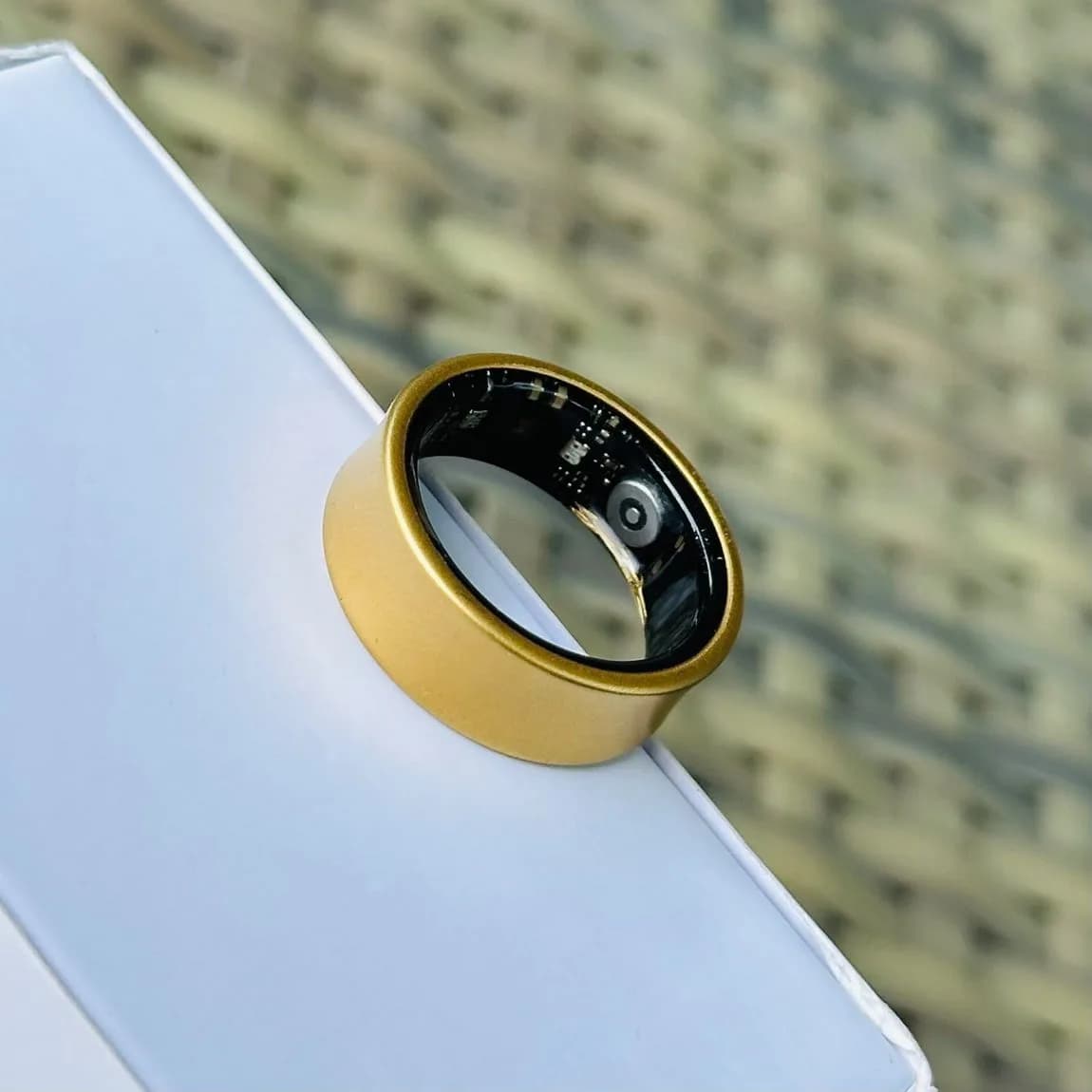 i do smart ring, gold finish, resting on a box edge